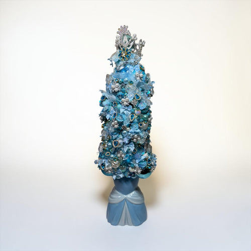 A decorative blue artificial flower tree with a silver crown topper and a blue ribbon bow at the base, photographed against a plain white studio background.