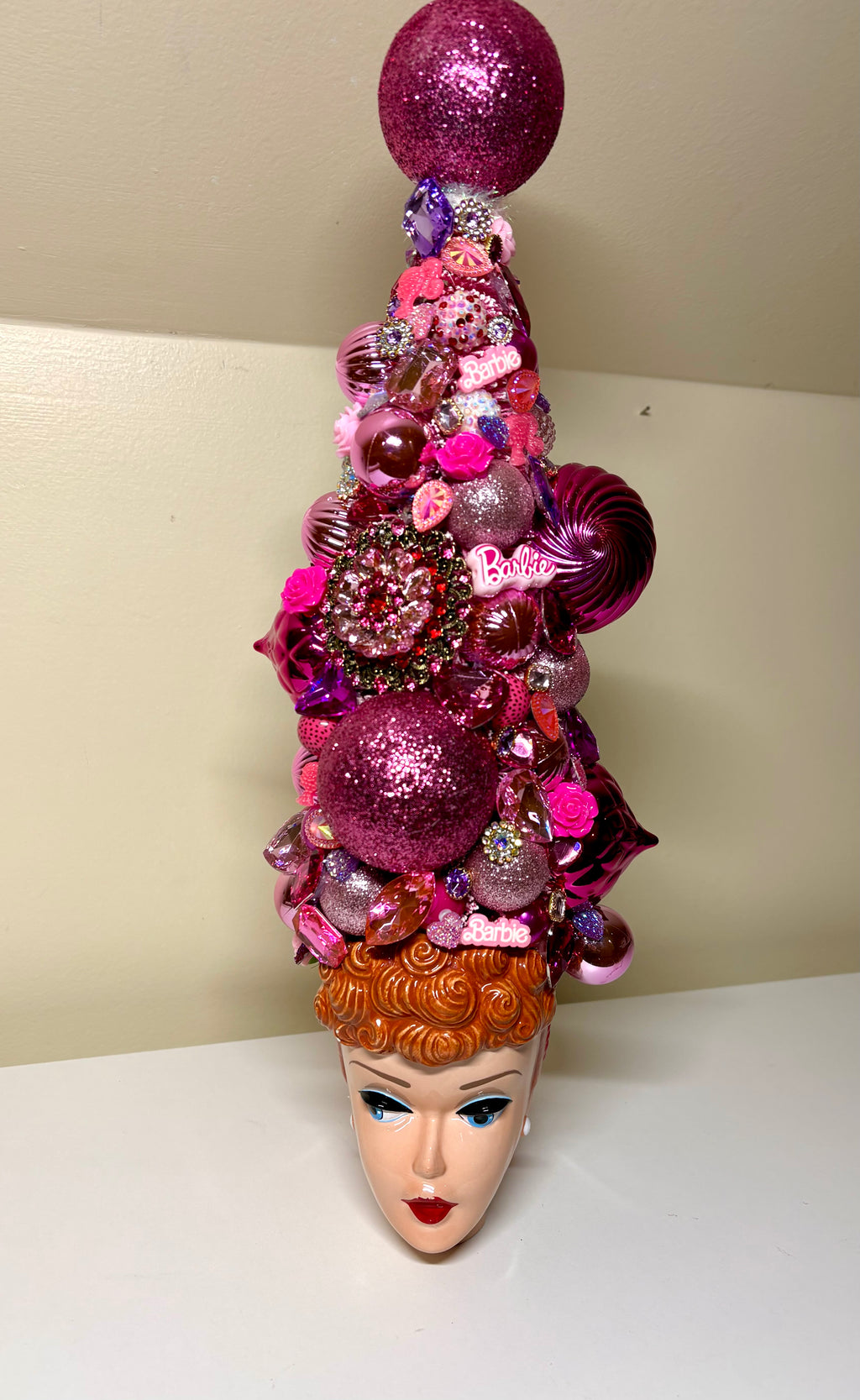 A handcrafted decorative 18 inch Christmas tree or table top tree, decorated with pink and purple ornaments, flowers, and baubles, displayed on a vintage Barbie Doll 3D ceramic mug, perfect for your entry way!