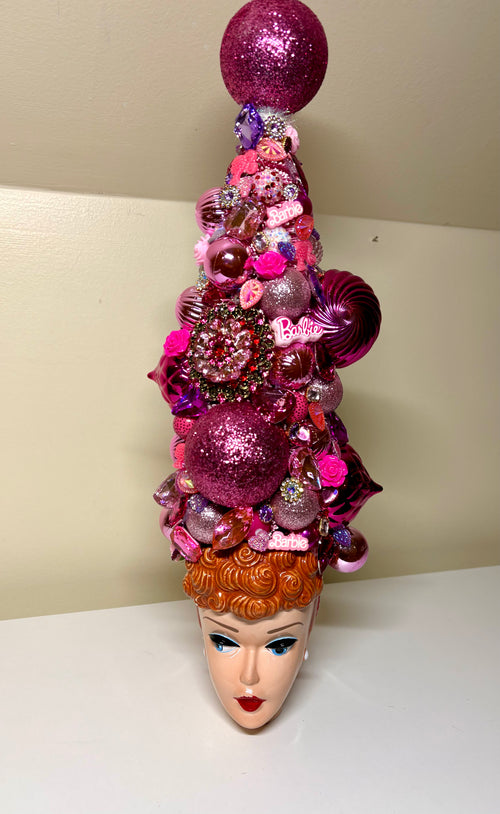 A handcrafted decorative 18 inch Christmas tree or table top tree, decorated with pink and purple ornaments, flowers, and baubles, displayed on a vintage Barbie Doll 3D ceramic mug, perfect for your entry way!