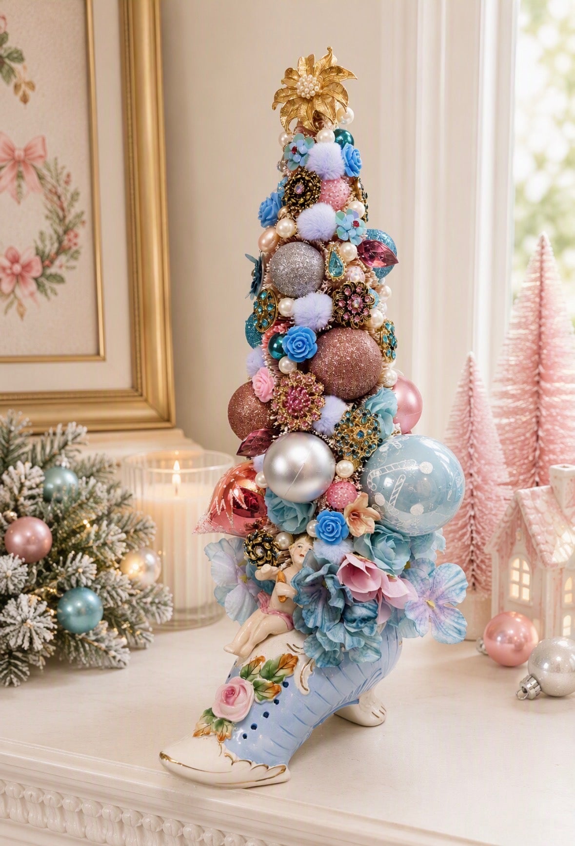 A decorative Christmas tree shaped like a light blue high-heeled shoe, decorated with pastel pom-poms, fabric flowers, glittery ornaments, and a gold star topper, displayed on a mantel in a softly lit room.