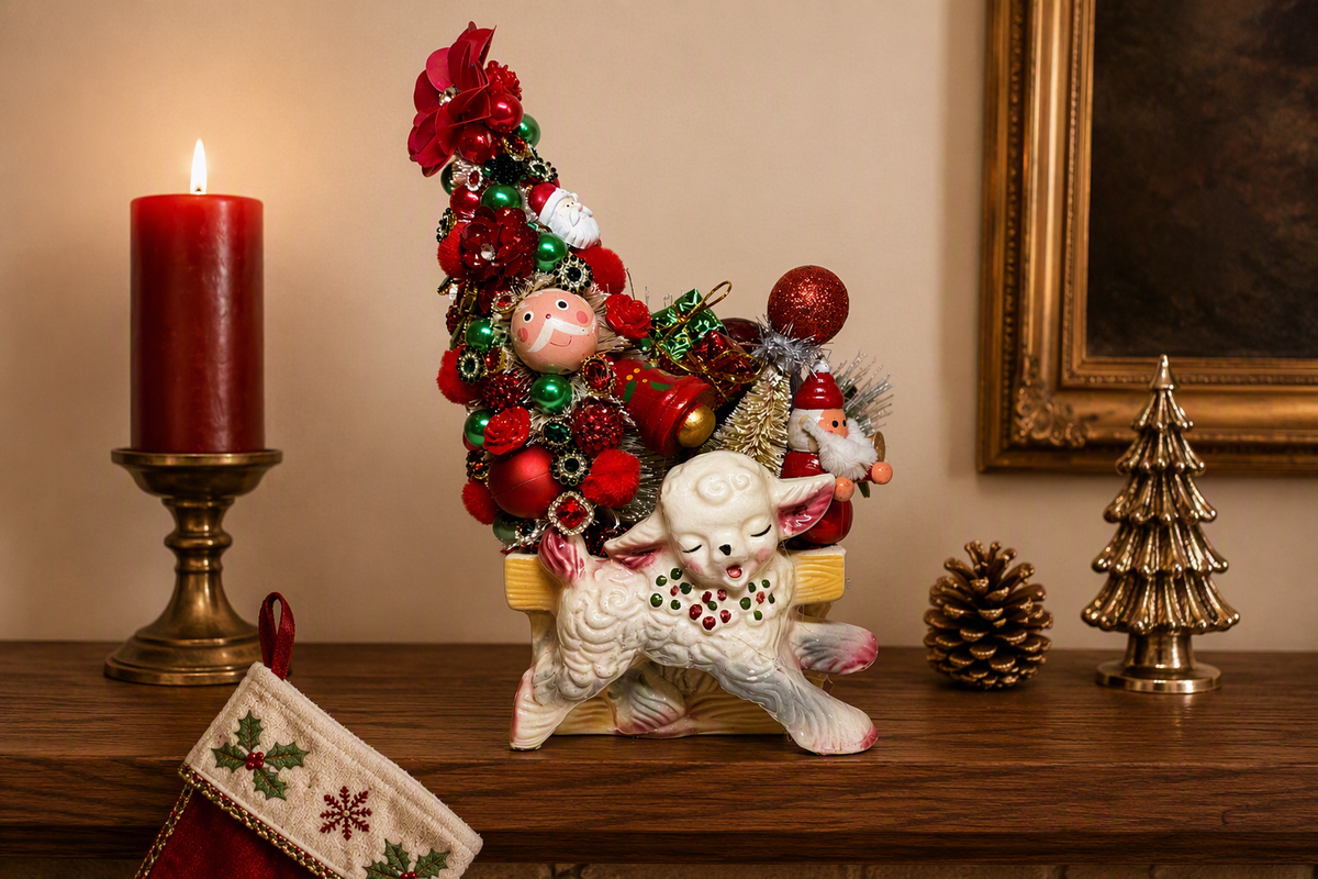 A festive Christmas ornament display featuring a white ceramic sheep figurine carrying a miniature Christmas tree decorated with red ornaments, green baubles, and Santa Claus details, set on a wooden mantel with a lit red candle, gold pinecone, and holiday stocking.