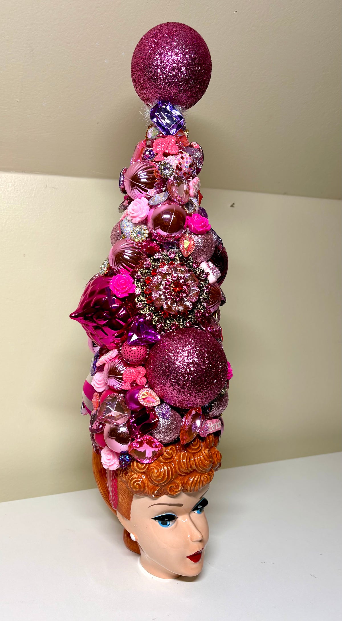 A fabulous decorative bejeweled doll themed Christmas or table top tree  made from pink and purple glittery ornaments, beads, sequins, and small embellishments, displayed in a vintage  Barbie 3D Mug